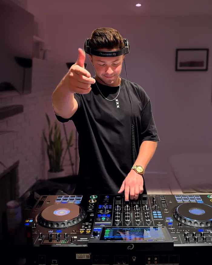 Don Vaughan pointing at the camera from behind the decks