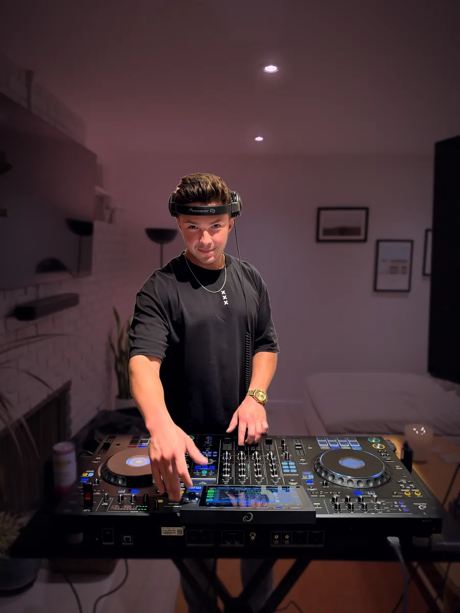 Don Vaughan behind the decks with his headphones on, looking into the camera